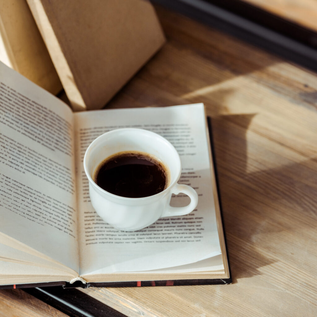 close up of open book with cup of coffee on bookshelf
